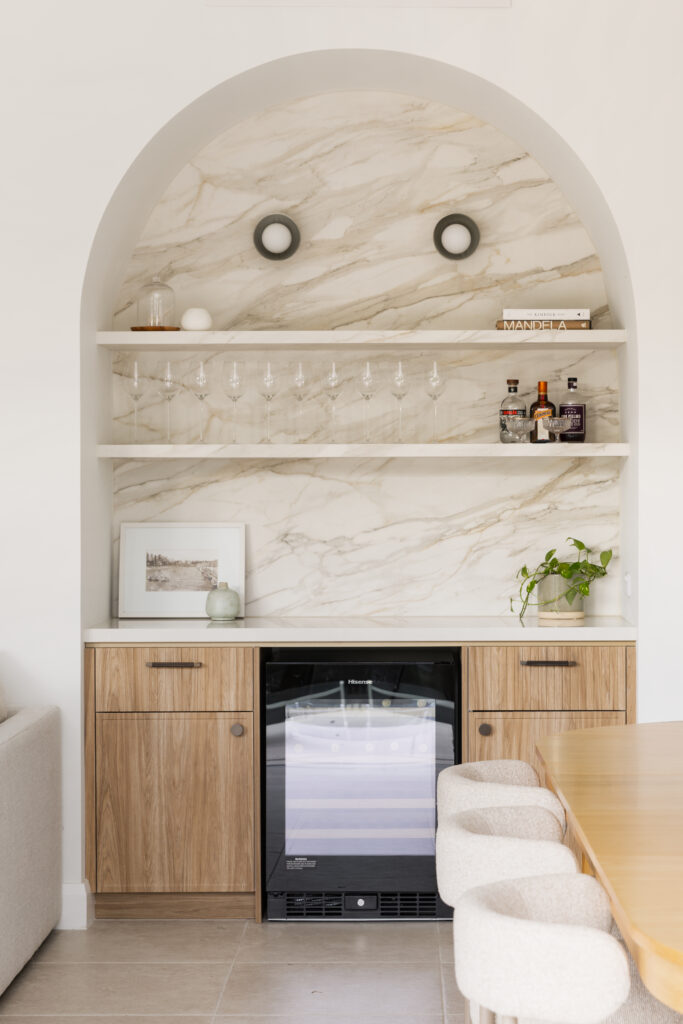 Close-up of Mirabel™ porcelain splashback in bar area with styled shelving, wine glasses and ambient lighting