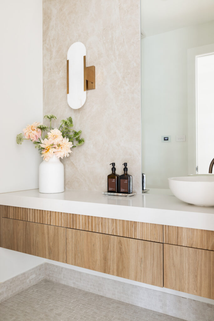 Bathroom interior with Organic White™ benchtop, brushed brass tapware, and timber vanity in Seaforth home