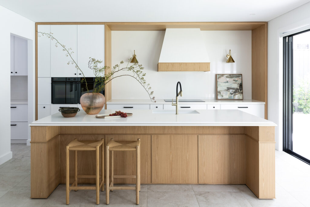 Open-plan kitchen with Aterra Blanca™ benchtop, fluted oak island and brass wall sconces