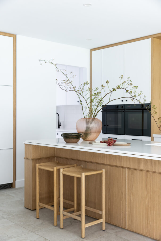Kitchen island detail with Aterra Blanca  surface, brass tapware and oak cabinetry