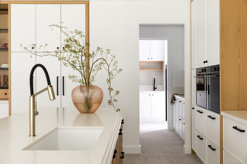 Kitchen view towards the butler’s pantry, revealing a cohesive palette of oak, white joinery and Aterra Blanca™