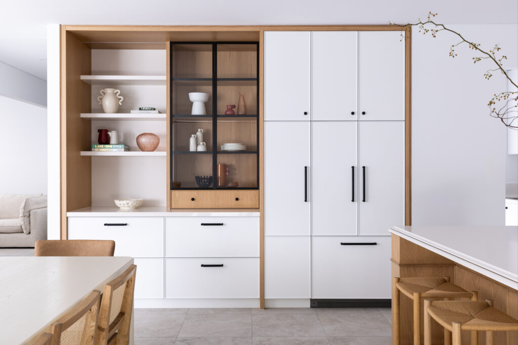 Custom oak-framed joinery combining open shelving, glazed display cabinetry and integrated storage