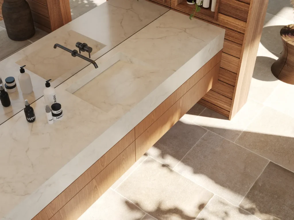 Image link Alt: Caesarstone<sup>®</sup> porcelain benchtop with an integrated basin, timber vanity cabinetry and sunlit, warm-toned stone flooring