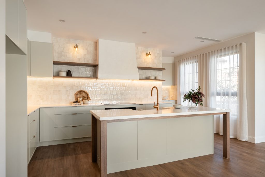 Light green kitchen island with Caesarstone<sup>®</sup> Frosty Carrina benchtop, zellige splashback tiles, and timber accents by Cook Constructions.