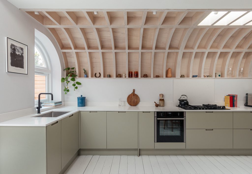 Deep olive sage cabinetry with Caesarstone<sup>®</sup> Frosty Carrina benchtop and arched timber ceiling by ROAR Architects.