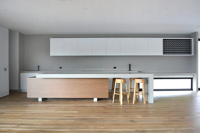 Coastal contemporary kitchen with white upper cabinetry, timber island base and a Caesarstone<sup>®</sup> Raw Concrete benchtop