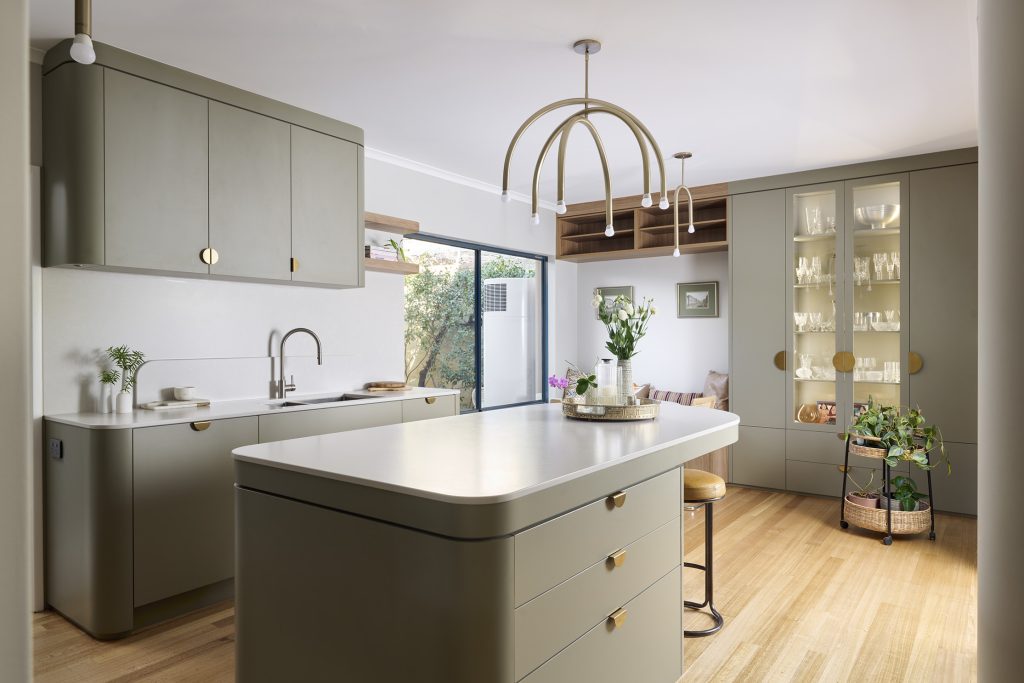 Muted sage green kitchen cabinets with rounded corners, brass hardware, and Caesarstone<sup>®</sup> Alpine Mist benchtops by Western Cabinets.