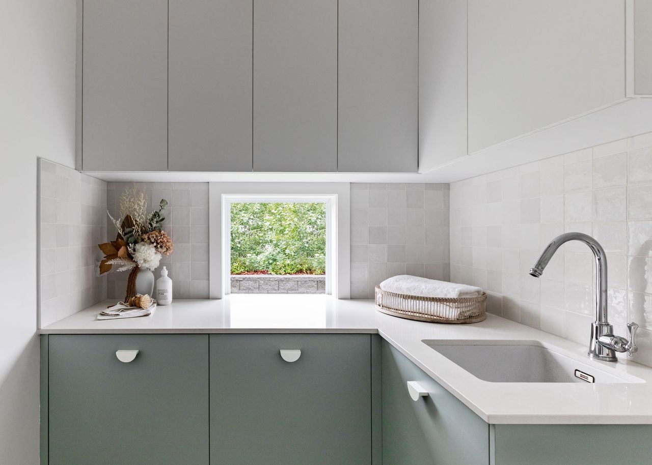 Laundry nook with a Caesarstone<sup>®</sup> Organic White countertop and sage green cabinetry.