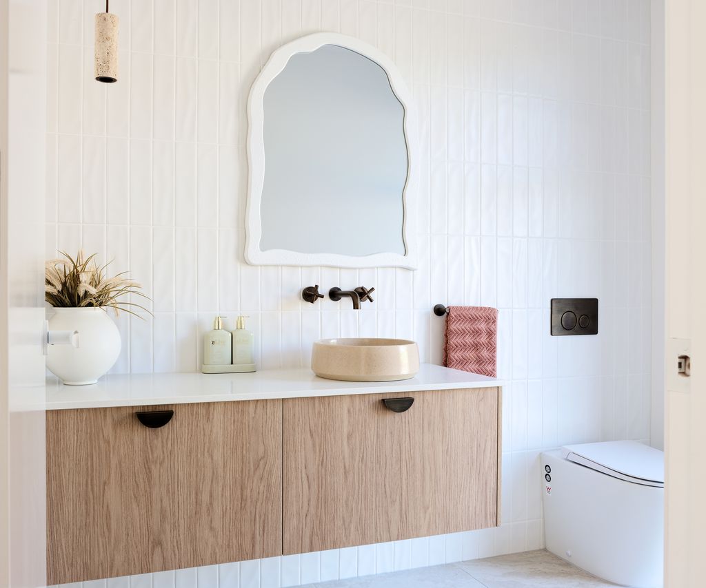 Timber bathroom vanity with a Caesarstone<sup>®</sup> Organic White top, round vessel basin and arched mirror.